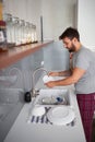 Young man washing dishes while standing in kitchen. Young people, interior, casual living concept Royalty Free Stock Photo