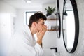 Young man washing face in the bathroom in the morning, daily routine. Royalty Free Stock Photo