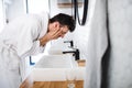 Young man washing face in the bathroom in the morning, daily routine. Royalty Free Stock Photo