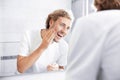 Young man washing face with soap near mirror Royalty Free Stock Photo