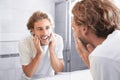 Young man washing face with soap near mirror Royalty Free Stock Photo