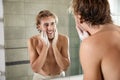 Young man washing face with soap near mirror Royalty Free Stock Photo