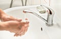 Young man washing hands under tap water with soap, focus on soapbar in background - importance of using lather for proper hygiene