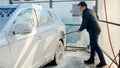Young man washing his car with foam and brush at carwash. Automobile care, transport cleaning, dirty car Royalty Free Stock Photo