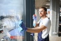 Young man washing window in office Royalty Free Stock Photo
