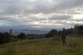 Young man watching a city from a viewpoint countryside landscape with colorful sunset Royalty Free Stock Photo