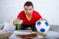 Young man watching football game on television looking excited and anxious sitting on sofa Royalty Free Stock Photo