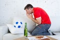 Young man watching football game on television nervous and excited suffering stress praying god for goal Royalty Free Stock Photo