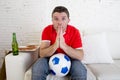 Young man watching football game on tv nervous and excited suffering stress praying god for goal Royalty Free Stock Photo