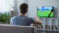 Young man watching soccer match home, criticizing football team for defeat