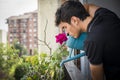 Young Man Watering Plants on Apartment Balcony