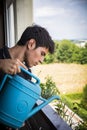 Young Man Watering Plants on Apartment Balcony