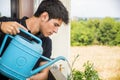 Young Man Watering Plants on Apartment Balcony