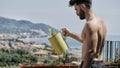 Young Man Watering Plants on Apartment Balcony