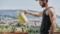 Young Man Watering Plants on Apartment Balcony