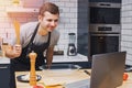 Young man in the kitchen looking for recipes on his laptop. Royalty Free Stock Photo