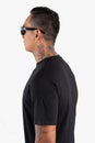 Young man wearing black t shirt  on white background. Young hipster man wearing t shirt and sunglasses in left side view Royalty Free Stock Photo