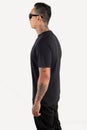 Young man wearing black t shirt  on white background. Young hipster man wearing t shirt and sunglasses in left side view Royalty Free Stock Photo