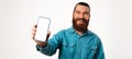 Young man wearing blue shirt holds mobile cell phone with blank screen. Royalty Free Stock Photo