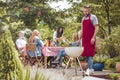 A young man wearing a burgundy apron cooking on a white grill. P