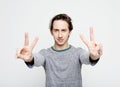 Young man wearing casua shirt smiling looking to the camera showing fingers doing victory sign