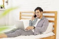 Young man wearing casual clothes at home, lying in bed using laptop to surf the Internet, reading/watching movies, chatting on the Royalty Free Stock Photo