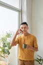 Young man wearing casual clothes talking on a mobile phone in the morning at a window Royalty Free Stock Photo