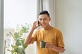 Young man wearing casual clothes talking on a mobile phone in the morning at a window Royalty Free Stock Photo