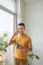 Young man wearing casual clothes talking on a mobile phone in the morning at a window Royalty Free Stock Photo