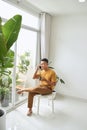 Young man wearing casual clothes talking on a mobile phone in the morning at a window Royalty Free Stock Photo