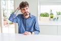 Young man wearing casual shirt sitting on white table confuse and wonder about question Royalty Free Stock Photo