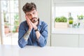 Young man wearing casual shirt sitting on white table sleeping tired dreaming and posing with hands together while smiling with Royalty Free Stock Photo