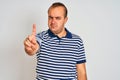 Young man wearing casual striped polo standing over isolated white background Pointing with finger up and angry expression, Royalty Free Stock Photo