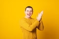 Young man wearing casual sweater over yellow background clapping and applauding happy and joyful, smiling proud hands together. Royalty Free Stock Photo