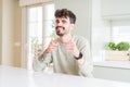 Young man wearing casual sweater sitting on white table pointing fingers to camera with happy and funny face Royalty Free Stock Photo