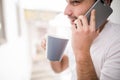 Young man wearing casual talking on a mobile phone in the morning at a window. Royalty Free Stock Photo