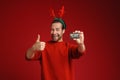 Young man wearing Christmas deer horns showing credit card and thumb up Royalty Free Stock Photo