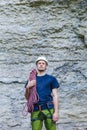 Young man wearing in climbing equipment with rope standing in front of a stone rock Royalty Free Stock Photo