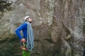 Young man wearing in climbing equipment with rope standing in front of a stone rock and preparing to climb Royalty Free Stock Photo