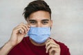 Young man wearing face mask portrait - Latin boy using protective facemask for preventing spread of corona virus Royalty Free Stock Photo