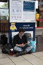 Young man wearing a face mask sititng on the floor of a bus station waiting Royalty Free Stock Photo