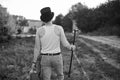 Young man, wearing grey pants, white top and black classic hat, holding old suitcase,and cane, walking away from camera. Black Royalty Free Stock Photo