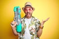 Young man wearing hawaiian flowers shirt holding water gun over yellow isolated background very happy and excited, winner Royalty Free Stock Photo