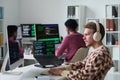 Young Man Wearing Headphones Coding Beside Black Man in Office Royalty Free Stock Photo