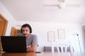Young man wearing headphones watching series, videos, online classes on a laptop with the fan on Royalty Free Stock Photo