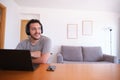 Young man wearing headphones watching series, videos, online classes on a laptop with the fan on Royalty Free Stock Photo