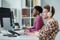 Young Man Wearing Headphones Working on Computer Beside Black Man Royalty Free Stock Photo