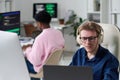 Young Man Wearing Headphones Working on Computer in Office Royalty Free Stock Photo