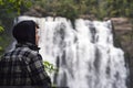 Young man wearing hoodie and admiring the nature in waterfall landscape. Inspirational concept