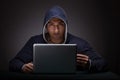 Young man wearing a hoodie sitting in front of a laptop computer